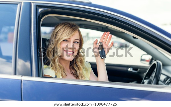 An attractive woman in a car
holds a car key in her hand. Rent or purchase of auto -
concept.