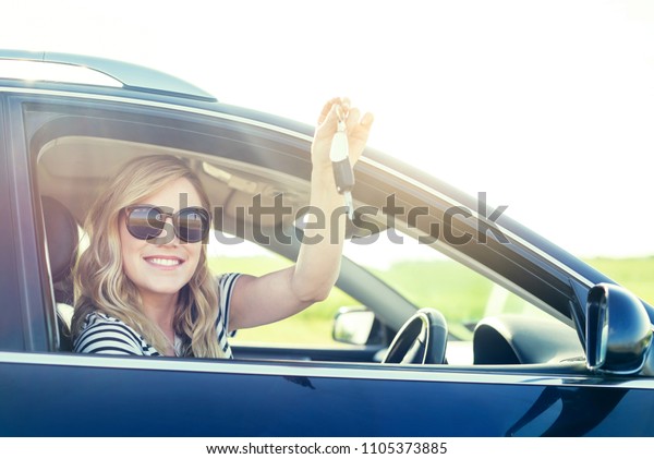 An attractive woman in a car
holds a car key in her hand. Rent or purchase of auto -
concept.