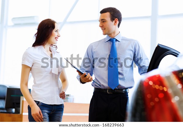 Attractive woman at car salon with consultant
choosing a car