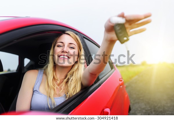 Attractive woman\
in a car showing keys at\
sunset.