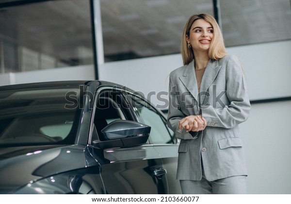 Attractive woman in\
car showroom buying a\
car