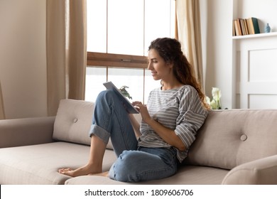 Attractive woman in casual clothes sit on couch use tablet device chat with friend on-line in social media net, freelance lady do remote distant job from home. Modern tech easy and comfy usage concept - Powered by Shutterstock