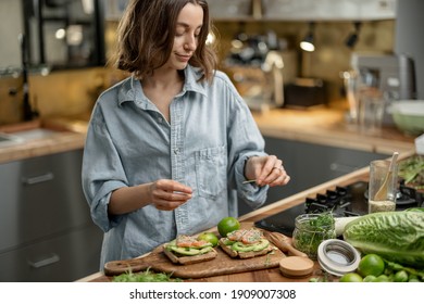 Attractive woman cooking healthy avocado toast in the home kitchen. Healthy eating and lifestyle concept. High quality photo - Powered by Shutterstock