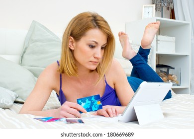 attractive woman with credit card and laptop laying in bad