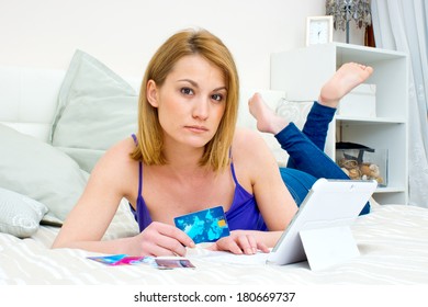 attractive woman with credit card and laptop laying in bad