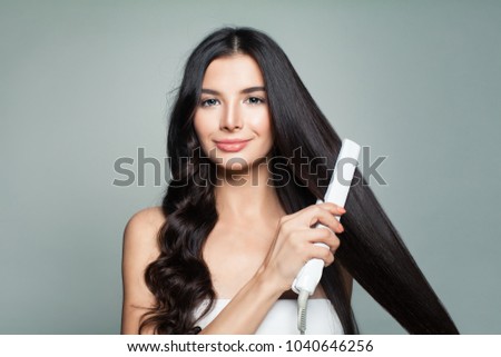 Attractive Woman with Curly Hair and Long Straight Hair Using Hair Straightener. Cute Smiling Girl Straightening Healthy Brunette Hair with Flat Iron. ストックフォト © 