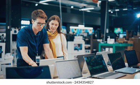 Attractive Woman Discusses Laptop Options with Home Electronics Store Sales Associate. Young Shopper Examines Modern Computer Choices with the Help of a Sales Expert in a Showroom. - Powered by Shutterstock