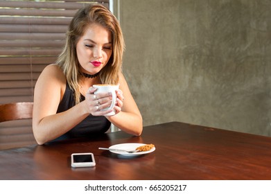 Attractive woman drinking a hot beverage at a wooden table