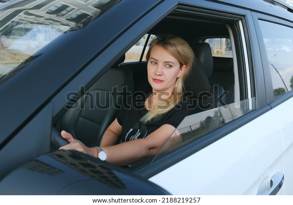 Attractive woman\
driving a car. A blonde woman with bright make-up is driving a car.\
Portrait of a serious\
woman.