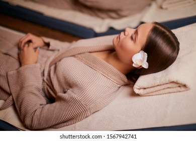 Attractive woman enjoy spending time in spa salon lying on bed in bathrobe and taking spa procedures. rest and comfort.