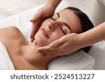 Attractive woman enjoying face massage, closeup. Beauty procedure