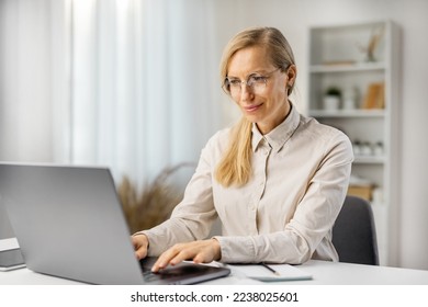 Attractive woman in eyeglasses working on laptop frm home, teacher having remote lesson, distant education.