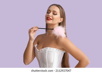 Attractive woman with feather stick from sex shop on color background