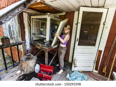 Attractive Woman Fixing A Swamp Cooler In A Rustic Cabin.