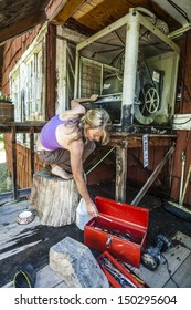 Attractive Woman Fixing A Swamp Cooler In A Rustic Cabin.