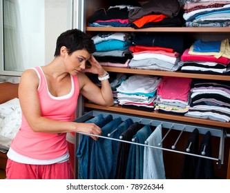 Attractive Woman In Front Of Closet Full With Clothes Thinking