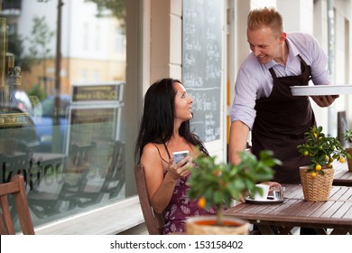 Attractive woman gets served her drink by a smiling waiter
