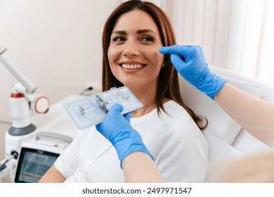 Attractive woman is getting a rejuvenating facial injections at beauty clinic. The expert beautician is filling female wrinkles with botulinum toxin injections or hyaluronic acid fillers. - Powered by Shutterstock