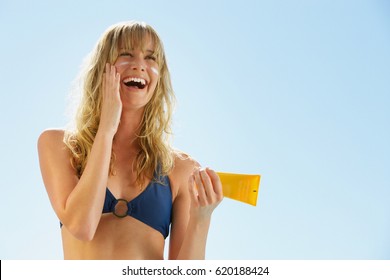Attractive woman with healthy skin applying sunscreen 