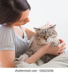 An Attractive Woman And Her Cat Relaxing On Pillows On Floor At Home