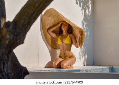 Attractive woman hiding from hot sun under big straw hat