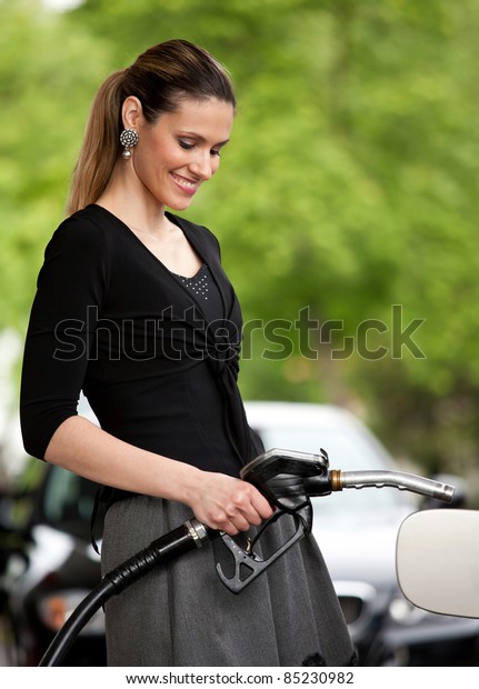 attractive woman\
holding nozzle at gas\
station