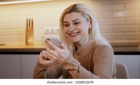 Attraktive Frau zu Hause mit Smartphone in der Küche senden Nachricht über die sozialen Medien teilen und mit Freunden zu verbinden lächeln