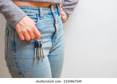 Attractive woman in jeans holding a bunch of keys. Keys near the pocket. Holding in hands house and bunch of keys.