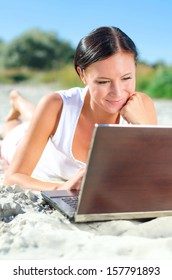 Attractive Woman With Laptop Lying On The Beach