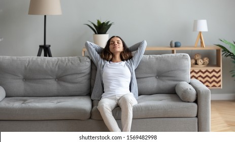 Attractive woman leaned on couch resting in living room. Female closed eyes put hands behind head enjoy fresh air, meditating feeling placidity and serenity, girl renew energy reduces fatigue concept - Shutterstock ID 1569482998