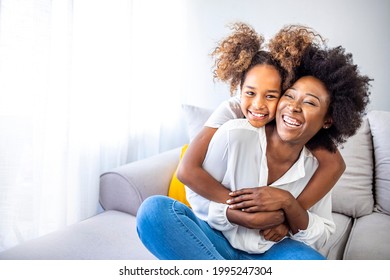 Attractive woman and little girl sitting on comfortable couch at home. Young mother talking communicates with small adorable daughter. Best friends happy motherhood weekend together with kid concept