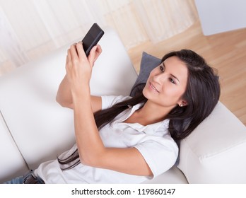 Attractive Woman With Long Straight Brunette Hair Smiling At The Camera And Talking On Her Mobile Phone