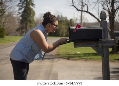 Attractive woman looks inside a mailbox.