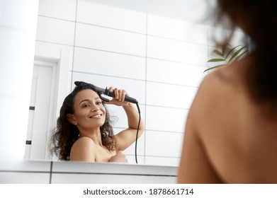 Attractive Woman Making Hairstyle. Beautiful Brunette Woman Twisting Hair In A Curling Iron.