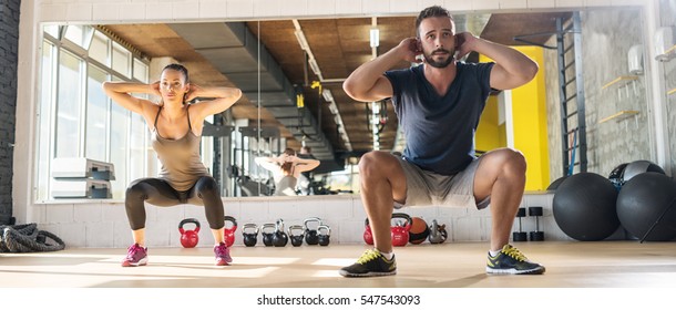 Attractive Woman And Man Exercising At Gym.