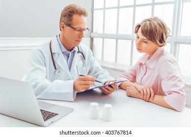 Attractive Woman Is On Consultation At Handsome Middle Aged Doctor At  Doctors Office