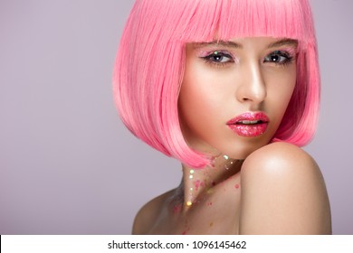 attractive woman posing with pink hair and glitter on face isolated on violet
