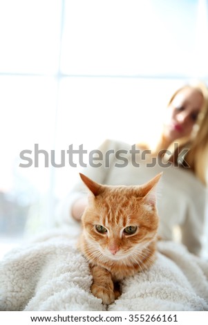 Attractive woman posing with red cat. Focus on cat