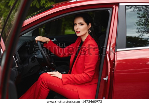 Attractive woman\
in red smart suit sitting in\
car