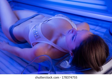 Attractive Woman Relaxing And Sunbathing On Tanning Bed.