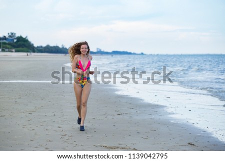 Attractive woman running along the beautiful beach of the sea during an amazing evening