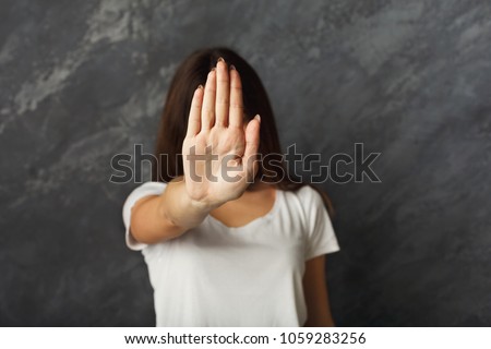 Attractive woman saying thanks but no. Beautiful girl denying proposal, making stop gesture, covering face with her hand, copy space