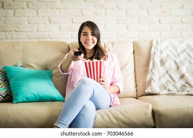 Attractive Woman Selecting A Movie To Watch On Tv While She Eats Popcorn In The Living Room