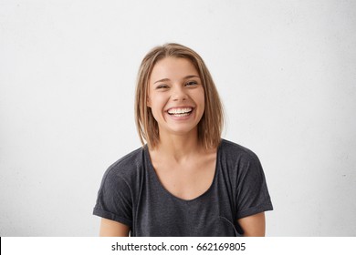 Attractive woman with short fair hair being very glad smiling with broad smile showing her perfect teeth having fun indoors. Joyful excited cheery femlae rejoicing after being proposed to marry - Powered by Shutterstock