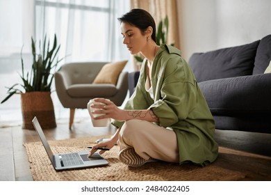 An attractive woman sits on the floor, working on her laptop with a cup of coffee in her hand. - Powered by Shutterstock