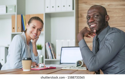 Attractive Woman Sitting At Desk In Office Having Takeaway Coffee.