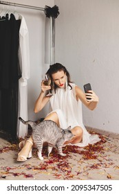 Attractive Woman Sitting In Evening White Event Dress And Celebrating Her Birthday, Christmas Or New Year. Holiday Concept, Happy Woman, Wine Glass With Champagne, Make Selfie, Cat. Focus On Phone.