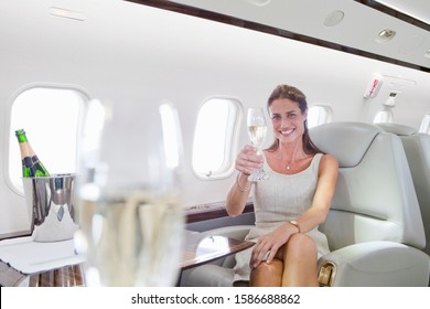 Attractive woman sitting and holding champagne glass in private jet