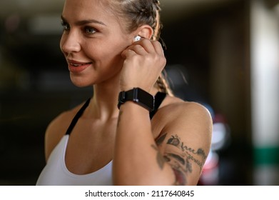 Attractive Woman In Sportswear Putting Airpods In Her Ears Before Training And Fitness Exercises Outside