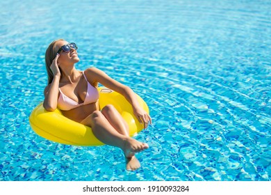Attractive woman in swimsuit in the yellow rubber ring in the swimming pool from above
